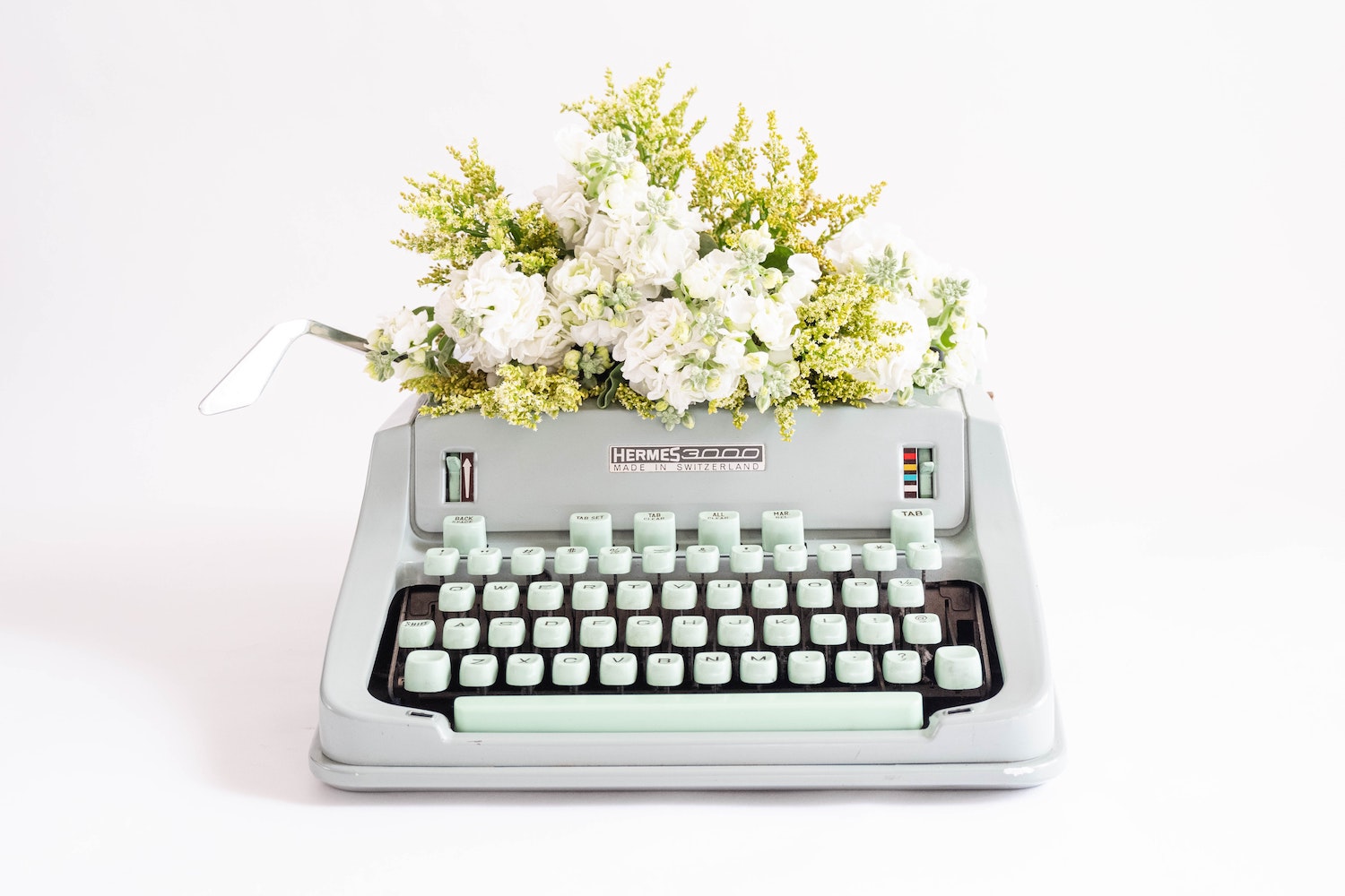 gray typewriter with white flowers on top