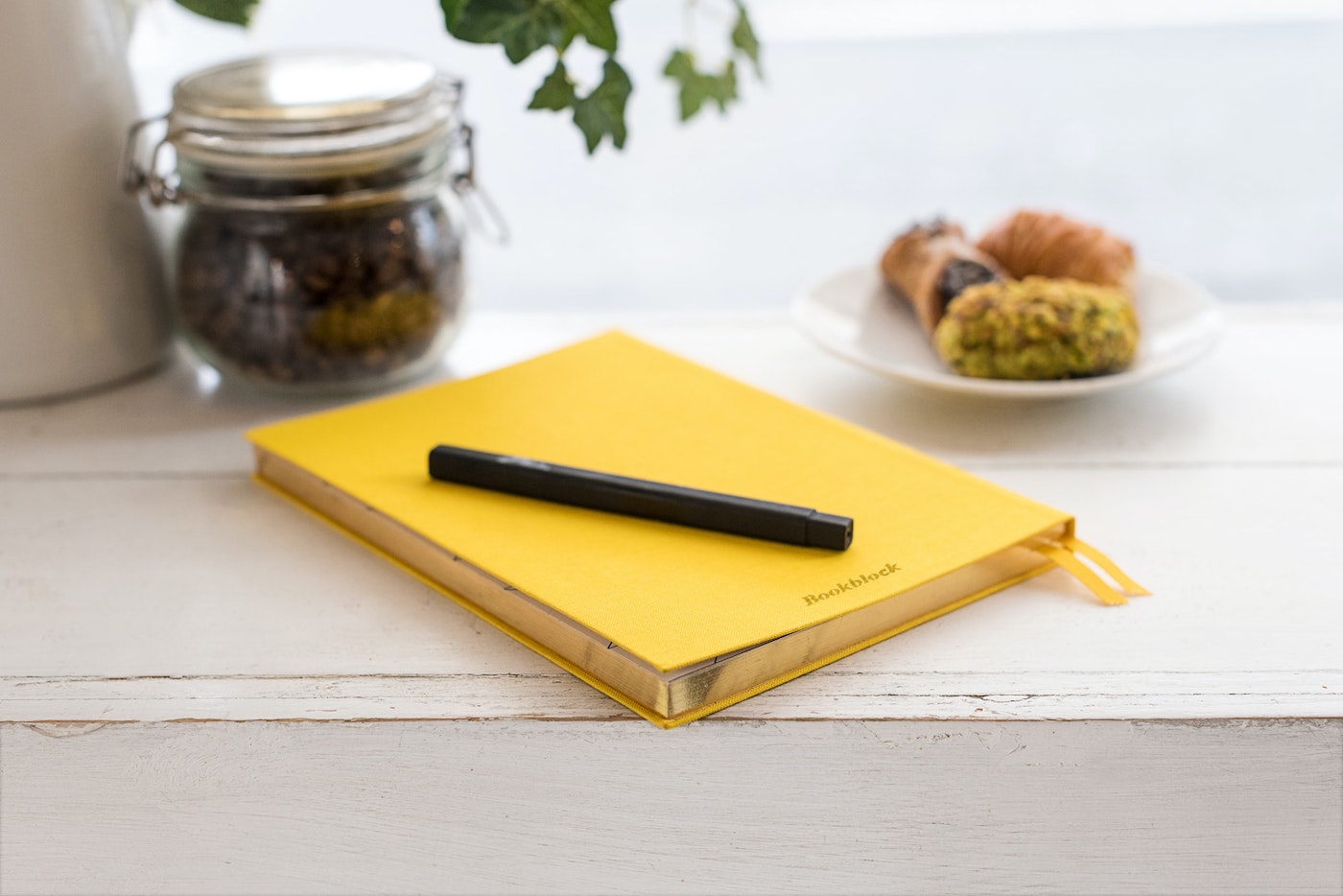yellow notebook on desk with black pen on top